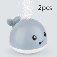 Blue and white whale bath toy with water spray and flashing lights for baby sensory play