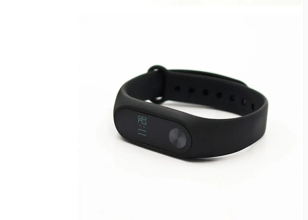 Black Xiaomi Mi Band 2 fitness tracker on wrist showing OLED screen with heart rate and step count.