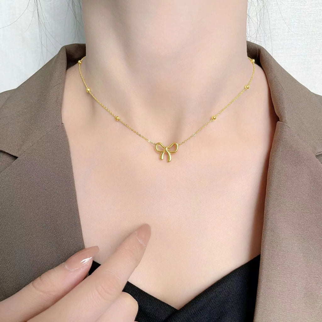Gold electroplated bow pendant fashion necklace on a cross chain, adjustable 41-50cm.