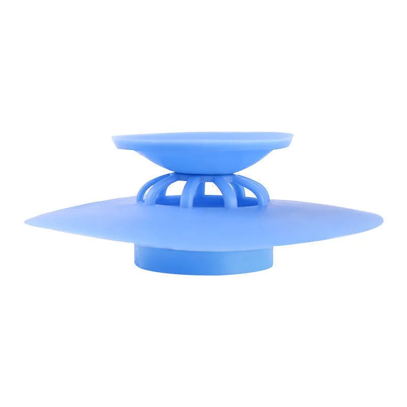 UFO-style silicone press sink drain cover in blue on a white basin, modern minimalist design