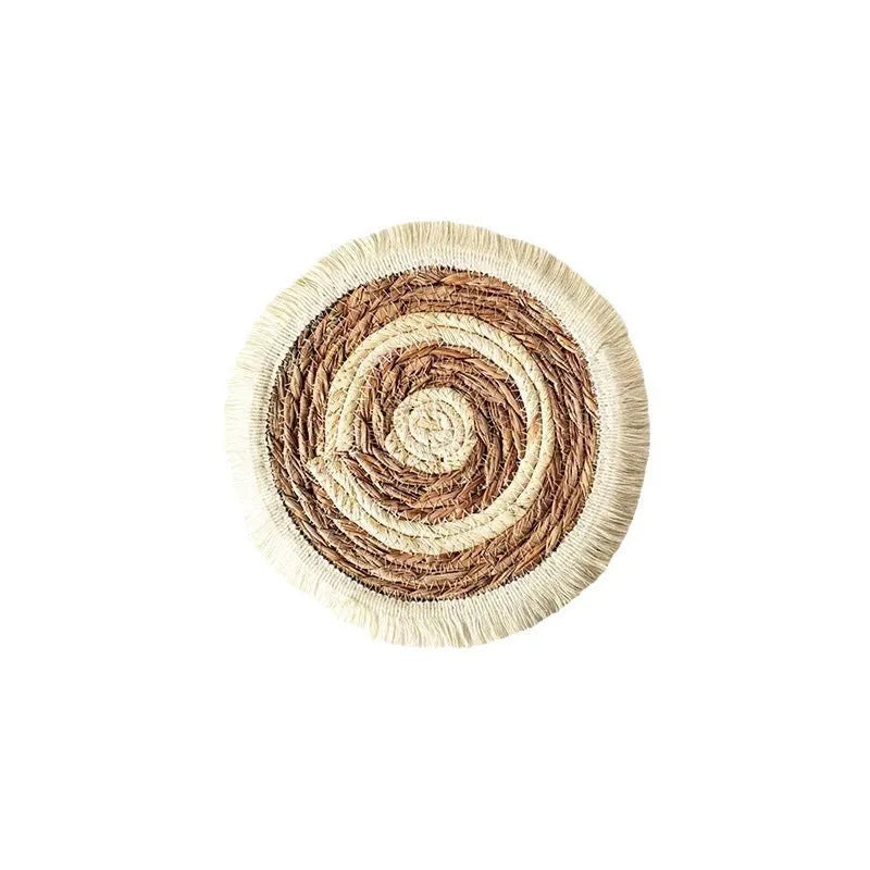 Round natural papyrus straw placemat with decorative tassels on a table