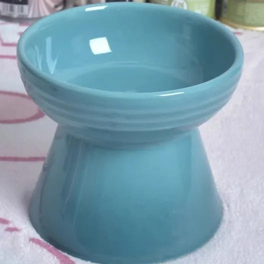 Black chin-high foot ceramic pet bowl for dogs and cats on a flat surface.