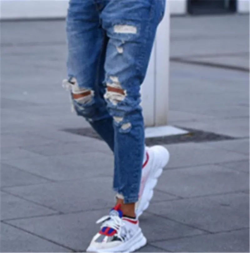 Men's deep blue distressed jeans with hole details on the legs.