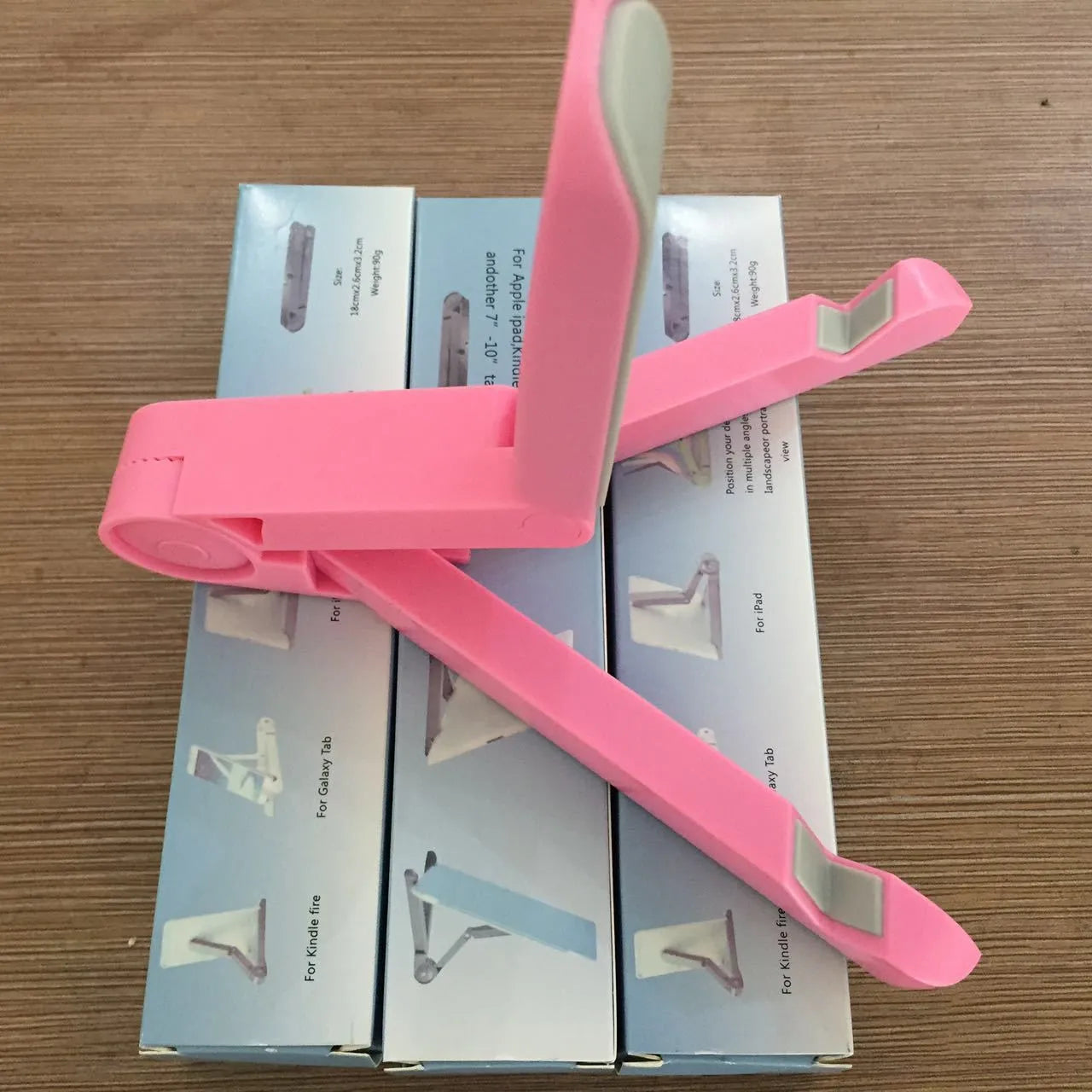 Black foldable tablet holder stand supporting a smartphone in landscape mode on a desk.