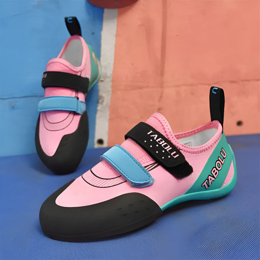 Beginner rock climbing shoes with Velcro straps and a coloured rubber sole on a climbing hold.