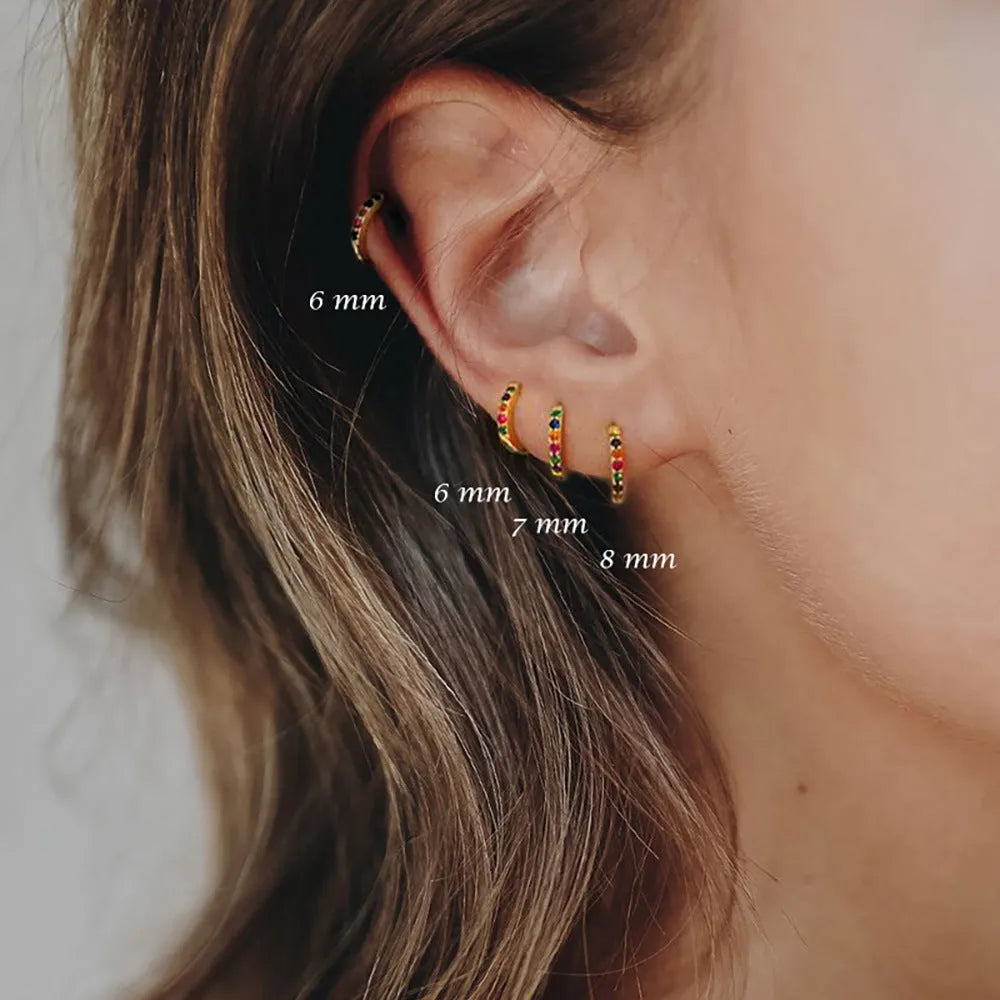 Perforated geometric circle stud earrings in gold, rose gold, and silver colours on a white background.