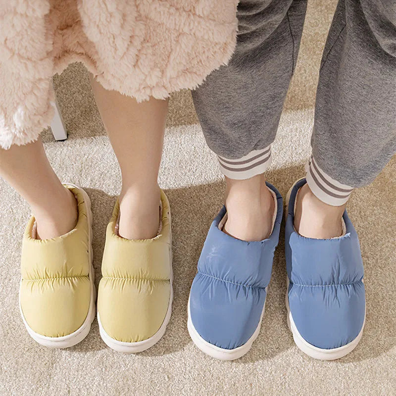 Pair of thick-soled indoor slippers in blue with a wrapped toe, low heel, and artificial plush lining.