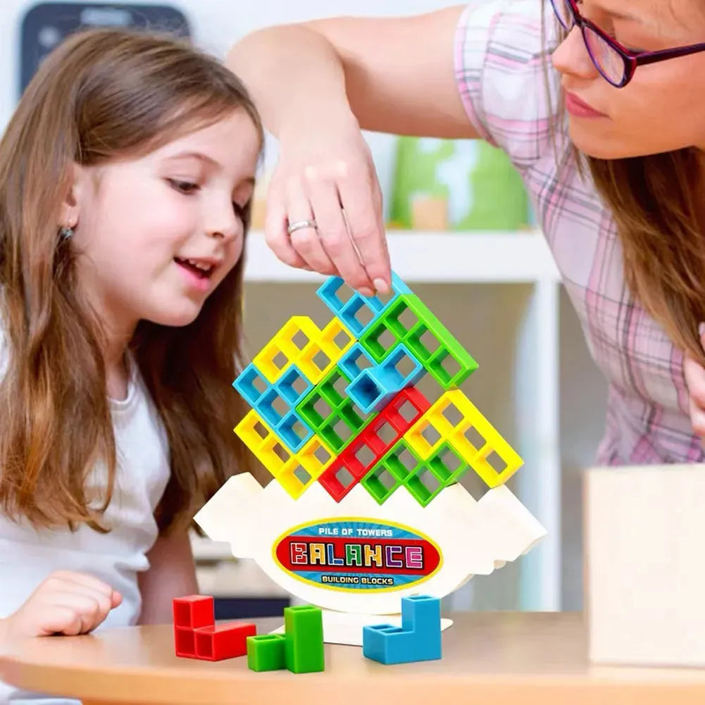 Plastic balance stacking board game with 16 coloured building blocks, chassis, and base on table.