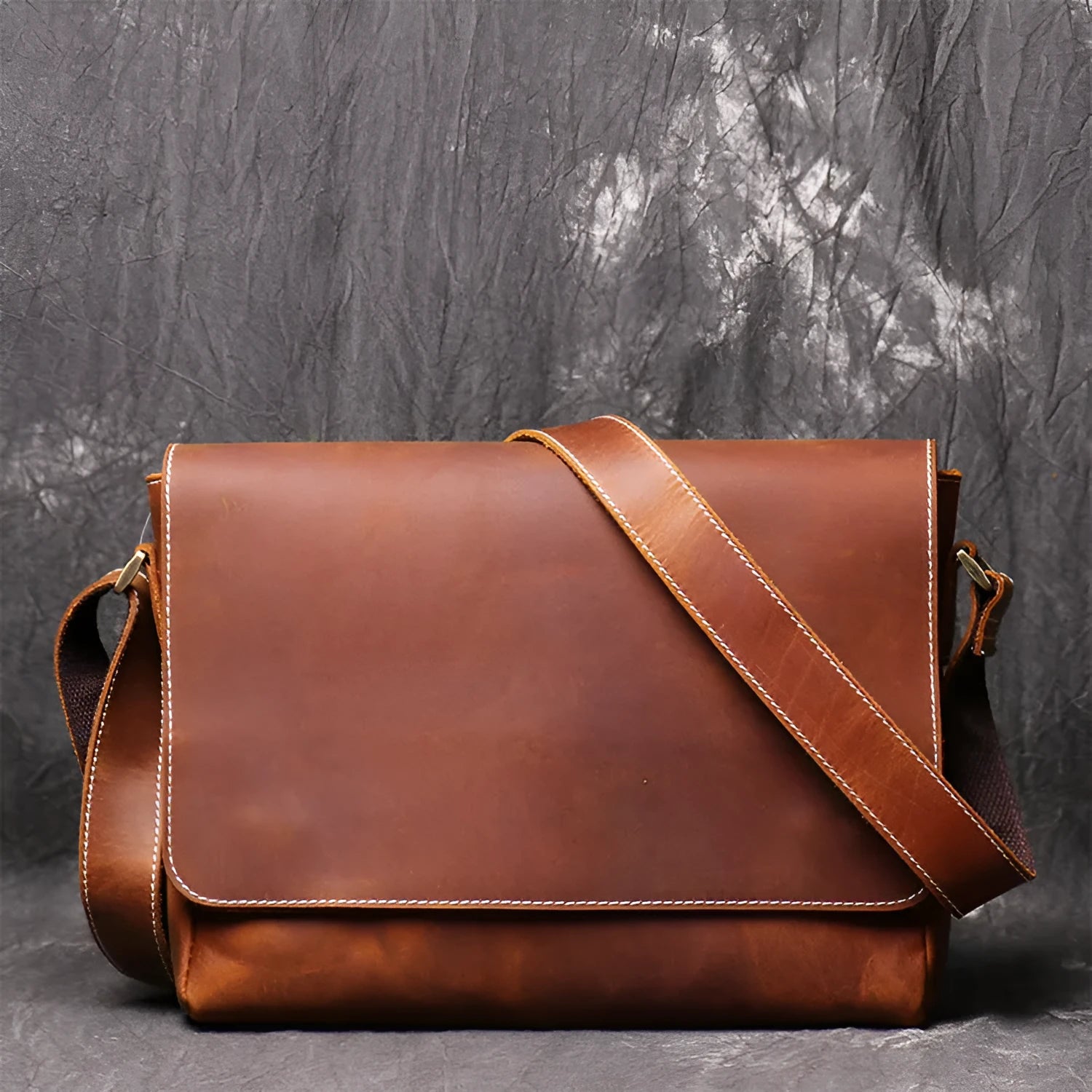 Men's vintage brown cowhide medium messenger bag showing front flap and long shoulder strap.