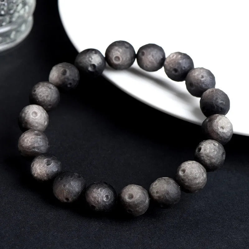 Obsidian crater ball bracelet with textured meteorite-like beads on elasticated cord