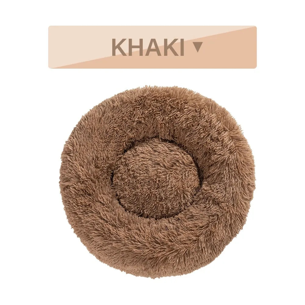 Fluffy donut-shaped dog bed in long plush material, shown in a light grey colour.