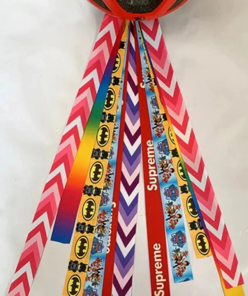 Colourful fabric helmet streamers for children's roller skating and ski helmets, shown in apricot, red, and grey.