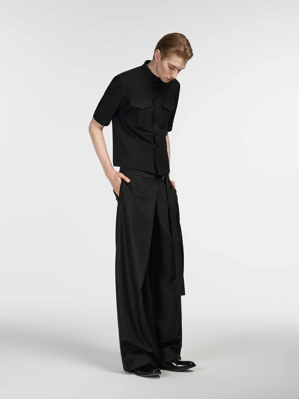 Black straight-leg Tencel cotton trousers with a single pleat and adjustable waistband on a hanger.