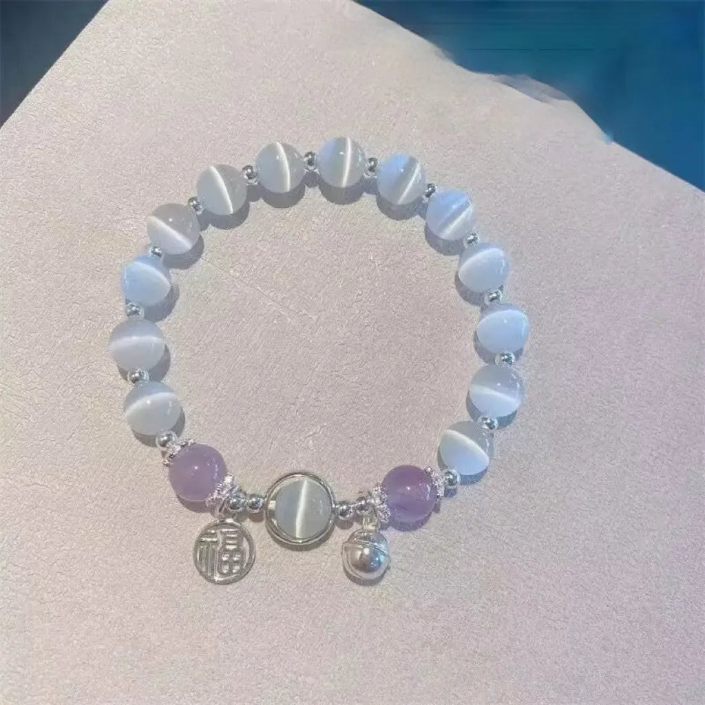 Close-up of a drop-shaped glass butterfly bracelet with round coloured beads on a wrist.