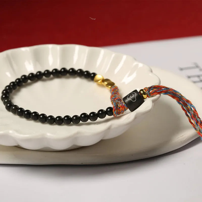 Hand-woven obsidian carrying strap bracelet with a stone bead, showing its 4mm width and adjustable length.