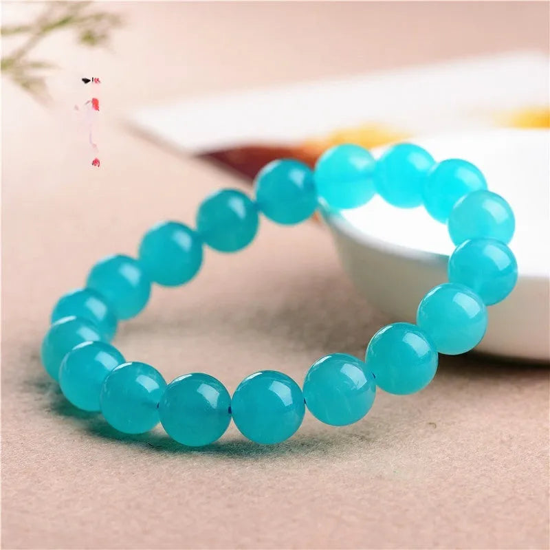 Natural blue-green Amazonite polished beads scattered on a surface, with a finished crystal bracelet.