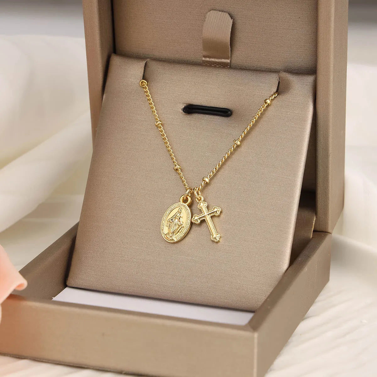 Gold-coloured geometric cross pendant necklace featuring the Virgin Mary, on a matching chain.