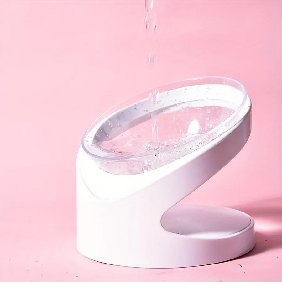 Clear plastic elevated cat food bowl with tilt design on white surface
