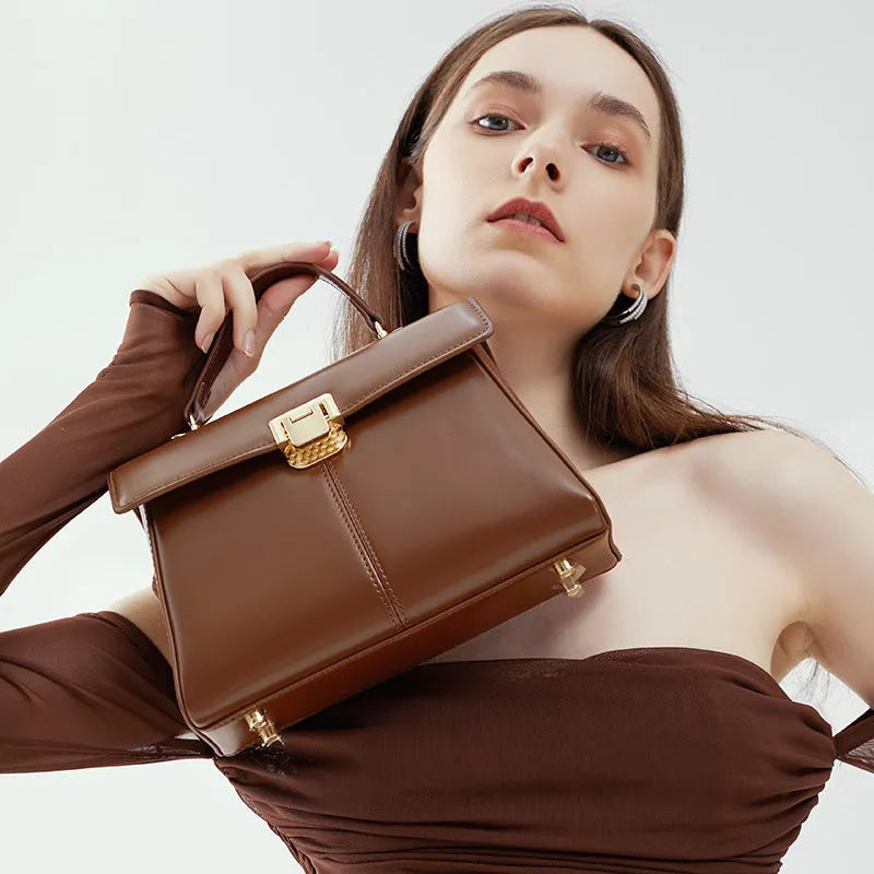 Women's black leather shoulder bag with vachette clasp, showing horizontal square shape and adjustable strap