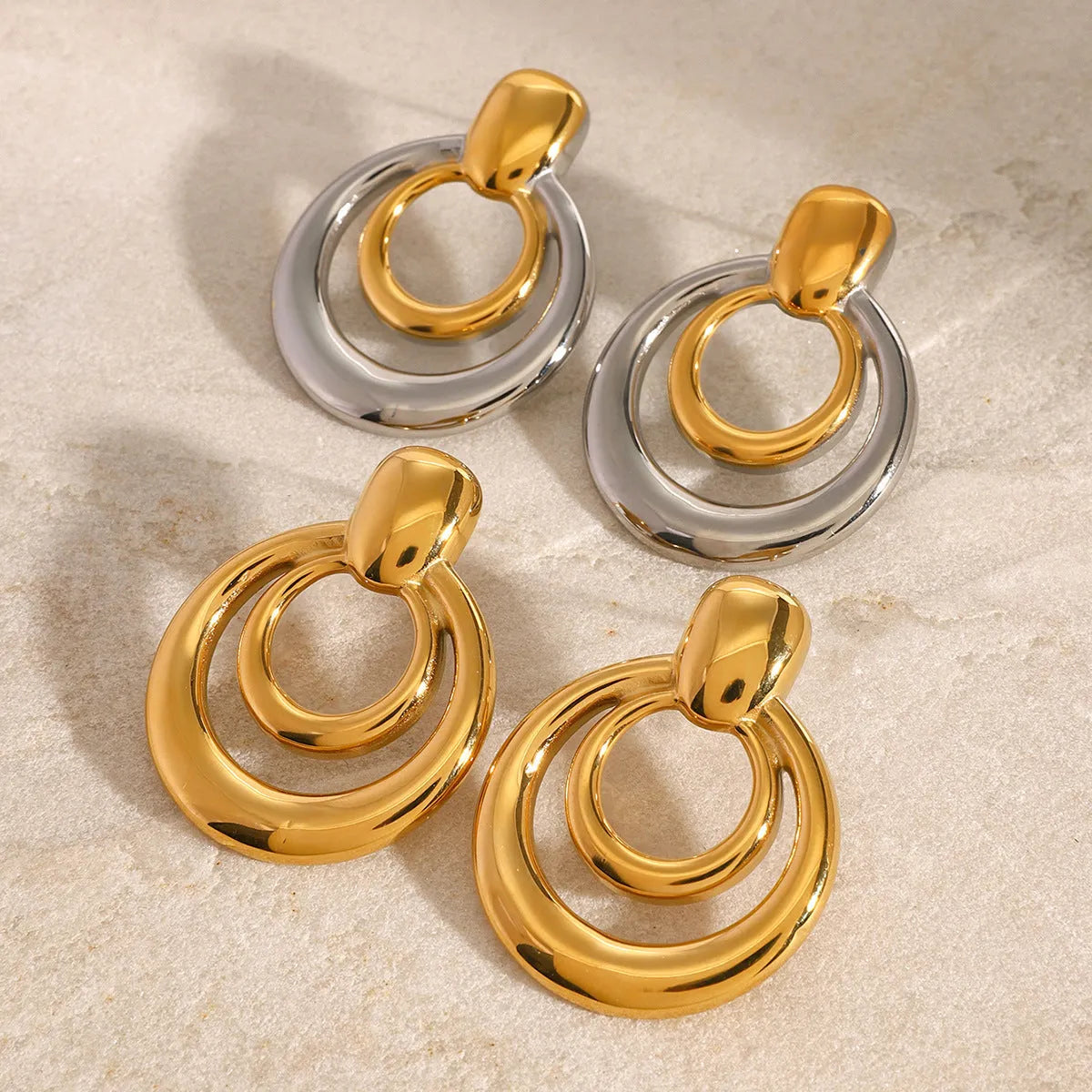 A pair of round gold-coloured geometric stud earrings with a double-layer hollow design.