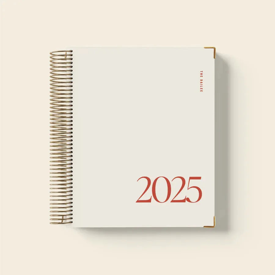 Cherry red coil notebook open to daily schedule pages showing spiral binding