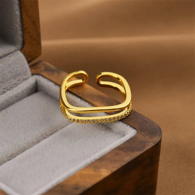 Gold geometric open fashion ring for women on a plain background.