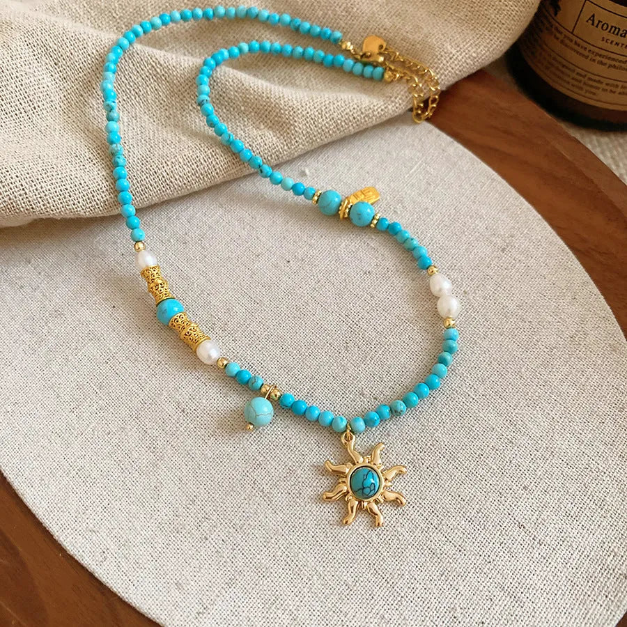 Freshwater pearl necklace with blue stone sun pendant on a gold-tone adjustable chain.