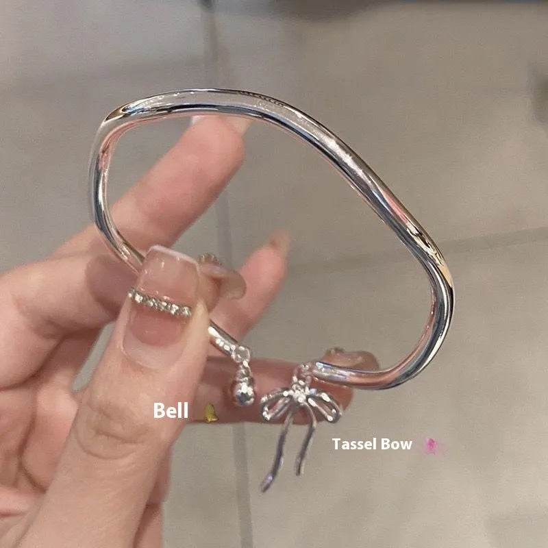 Silver bow charm adjustable bracelet with electroplated finish and bell opening mechanism