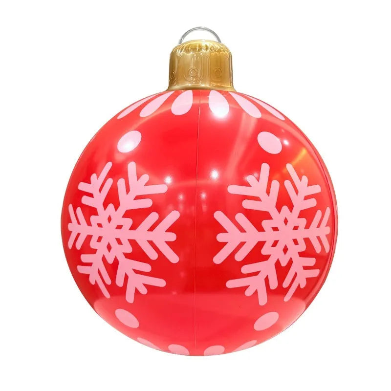 Large red and white inflatable Christmas ball with flashing lights in a garden setting.