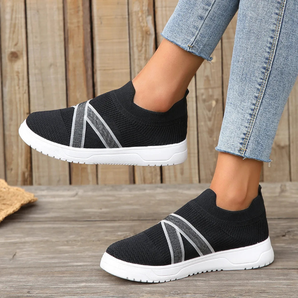 Black women's casual trainers with flyknit mesh upper, flat rubber sole, round toe, and a tassel detail.