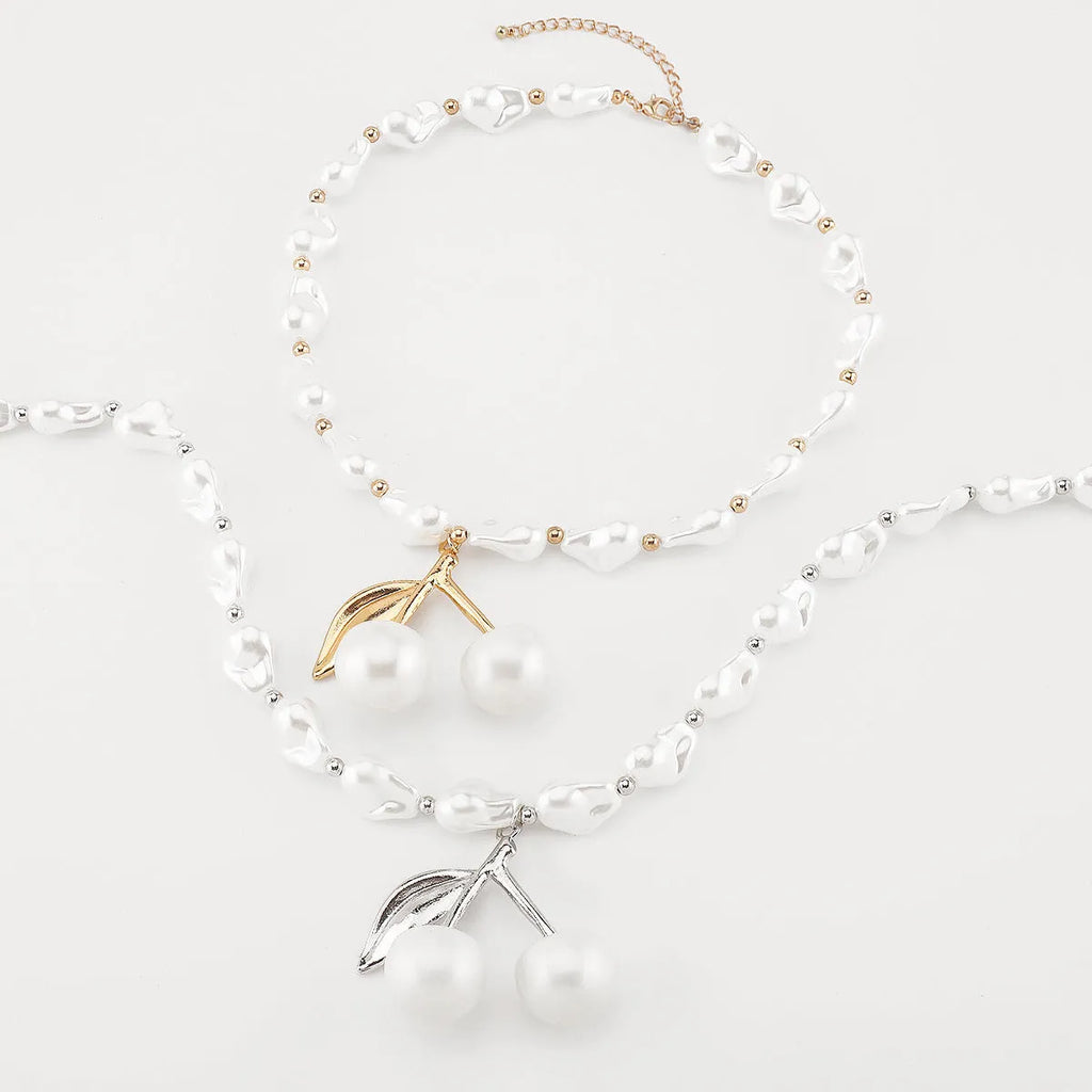 Gold and white alloy necklace with irregular cherry fruit and pearl pendant on a pearl chain.