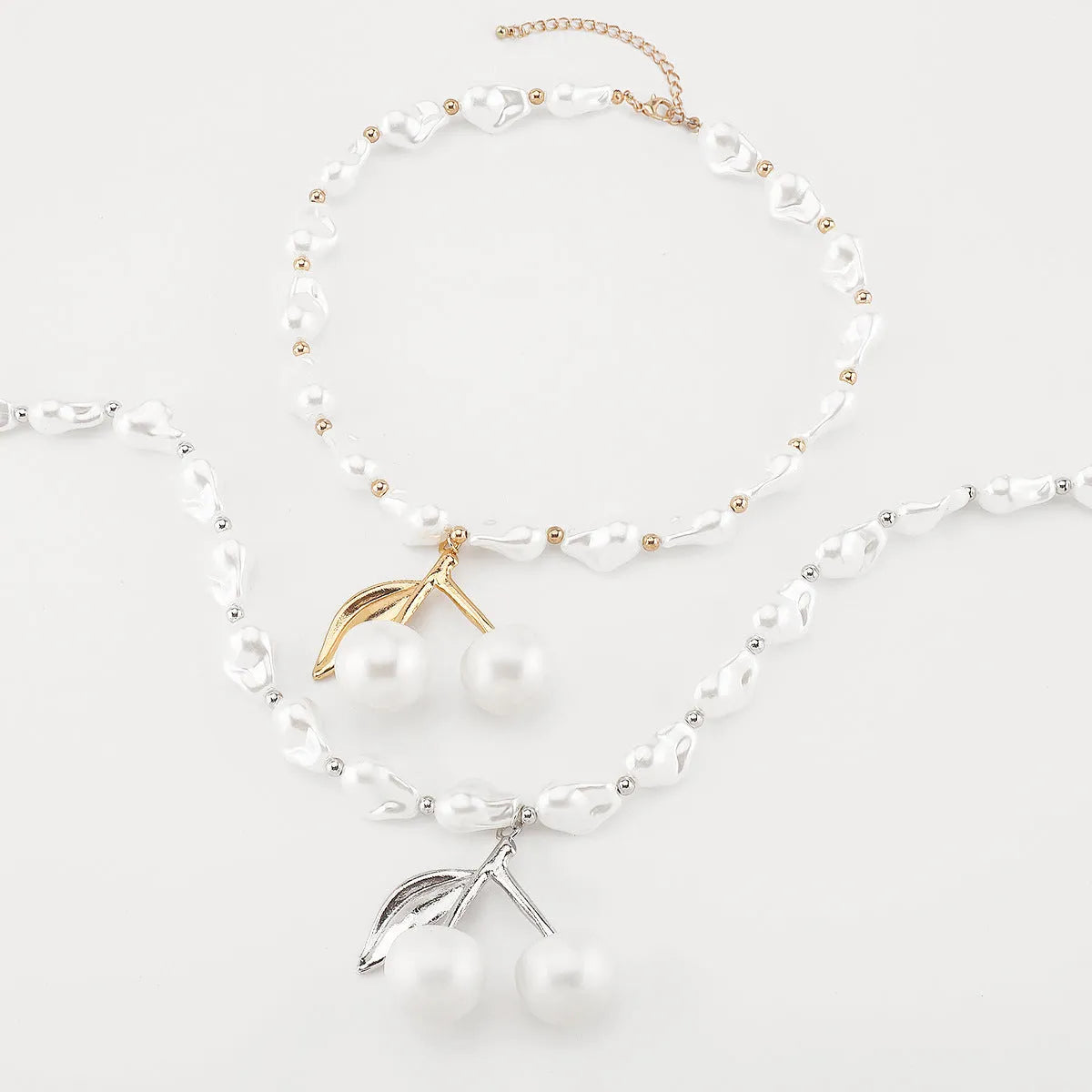 Gold and white alloy necklace with irregular cherry fruit and pearl pendant on a pearl chain.