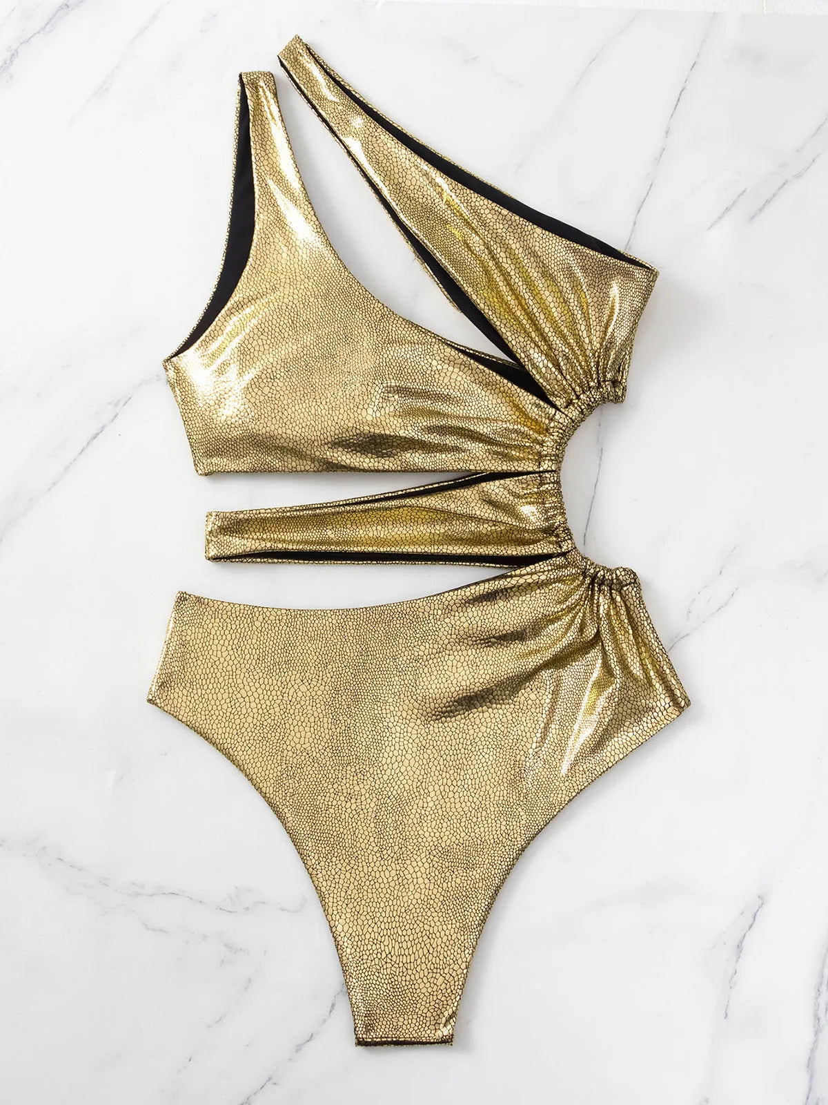 Women's gold one-piece backless swimsuit made from spandex, shown on a model.