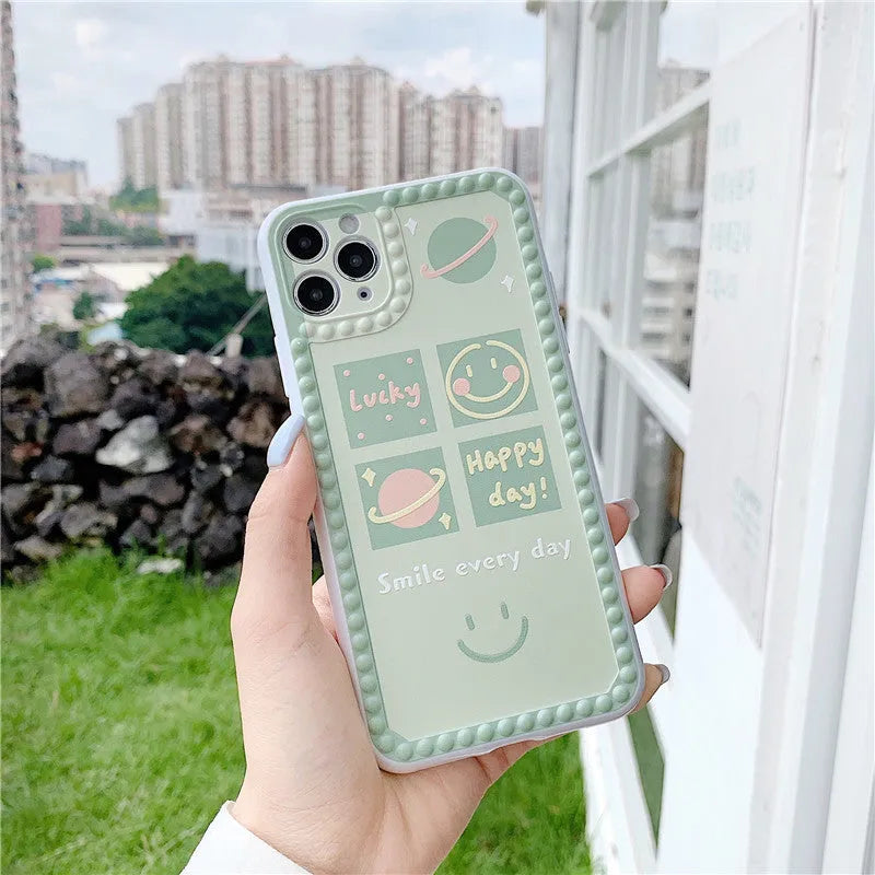 Green iPhone case with smiley face and white polka dot geometric design on the back.