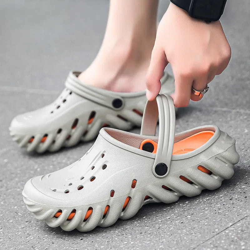 Men's beige EVA slipper sandals with hollow-out design and non-slip sole, shown on a wooden deck.