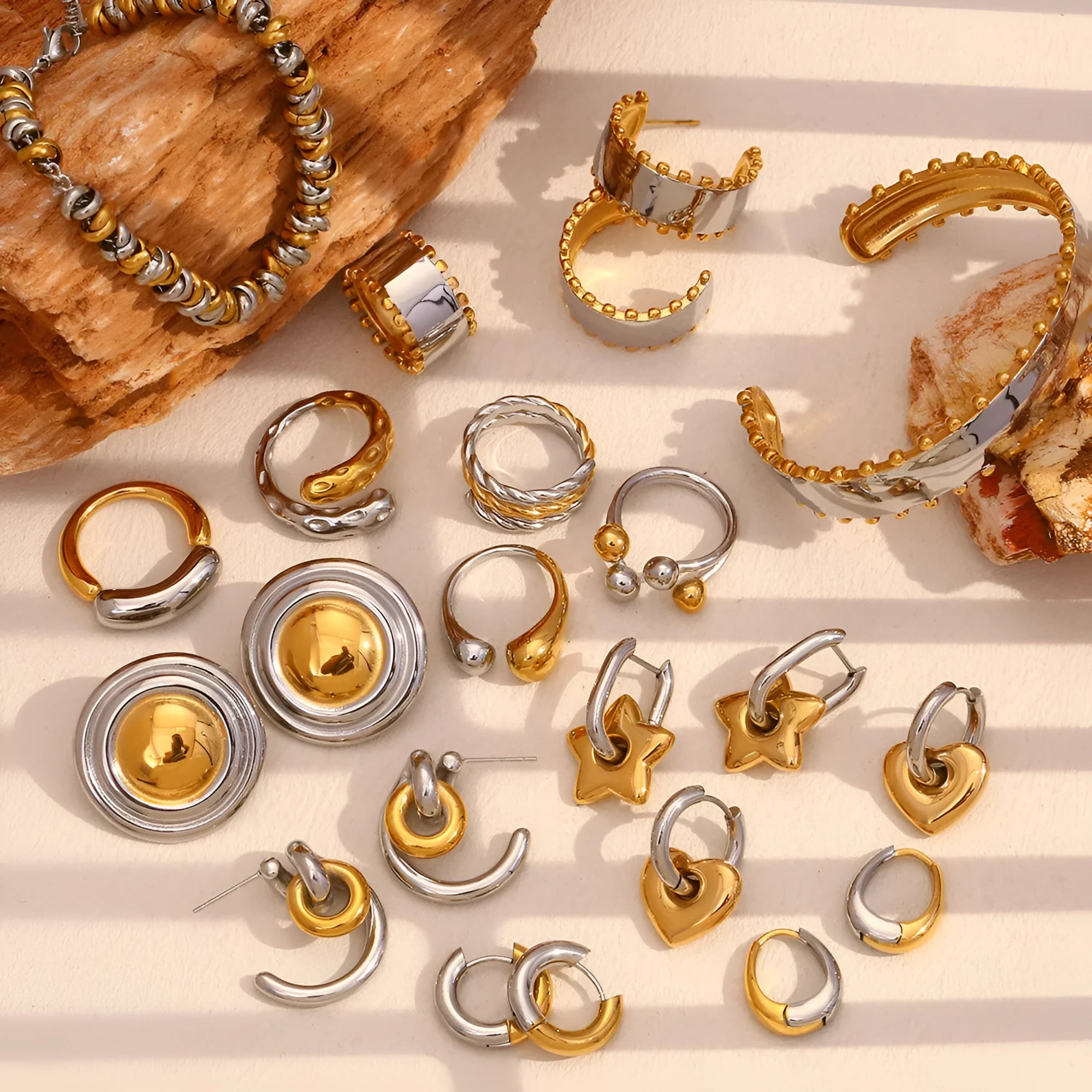 Gold geometric stainless steel earrings, bracelet, and necklace set on a white background.