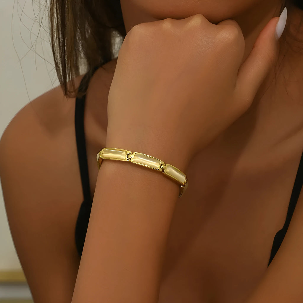 Women's geometric rose gold opal bracelet with quadrilateral shape and gemstone inlay on a plain background