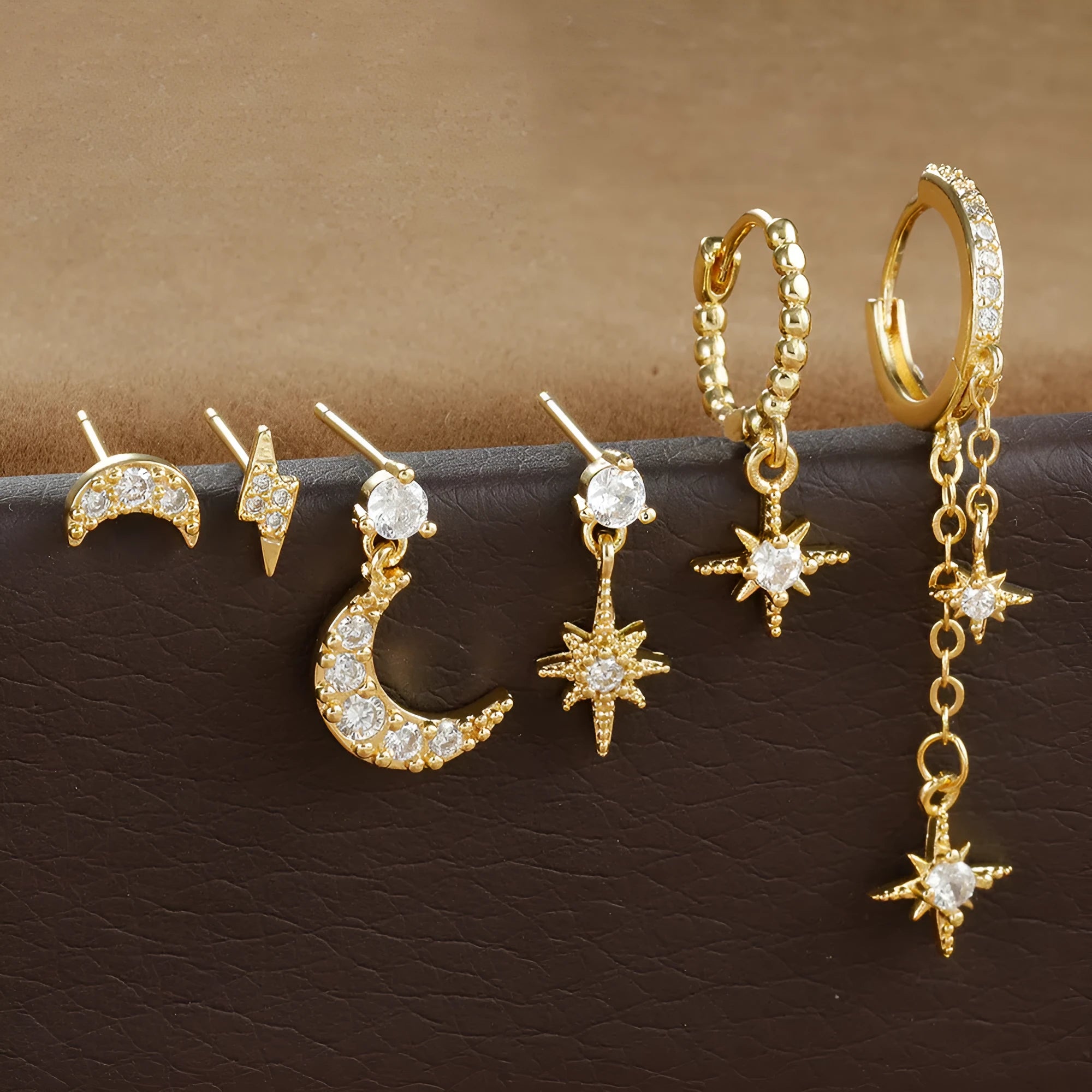 Six pairs of gold chain tassel earrings with zircon studs in display layout