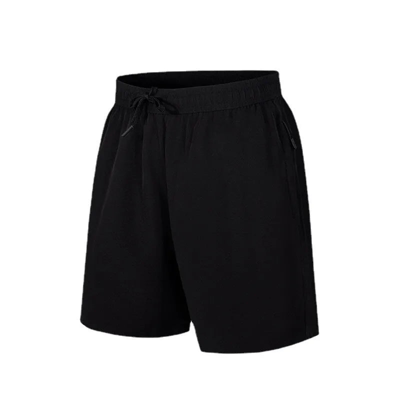 Man wearing loose-fit black quick-drying ice silk polyester sports shorts on a beach.