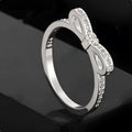 Silver bow-shaped ring with rhinestone and zircon crystal details on a model finger.