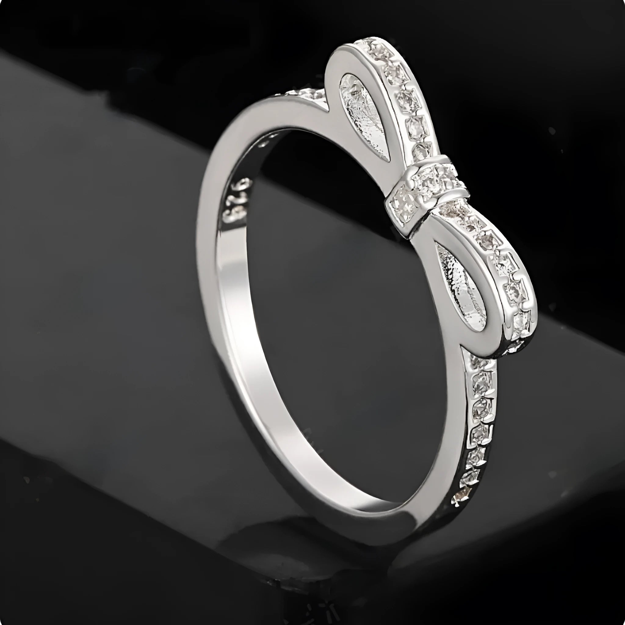 Silver bow-shaped ring with rhinestone and zircon crystal details on a model finger.