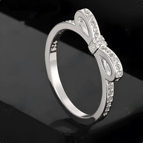 Silver bow-shaped ring with rhinestone and zircon crystal details on a model finger.