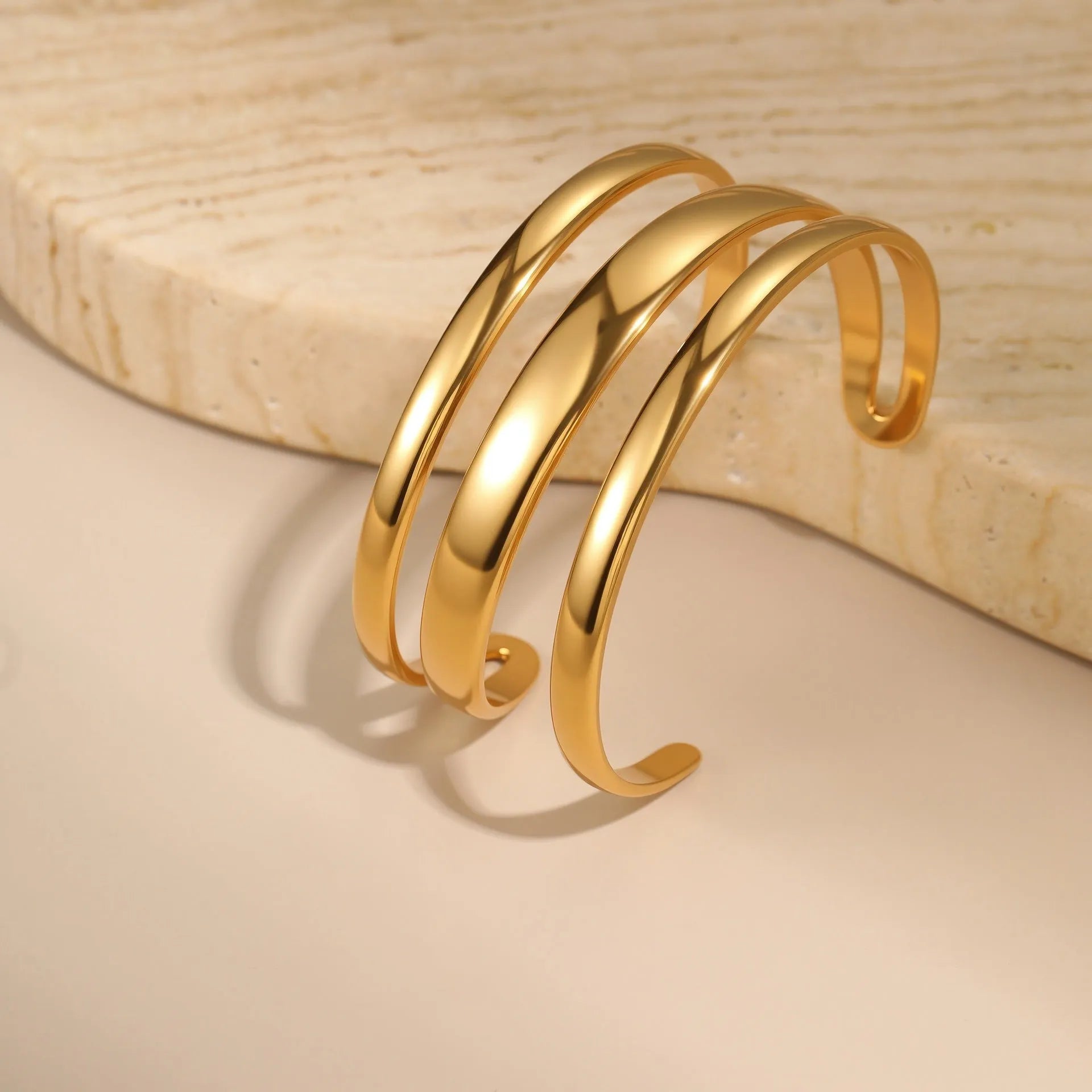 Geometric stainless steel women's bracelet with a simple opening, shown in gold and steel colour options.