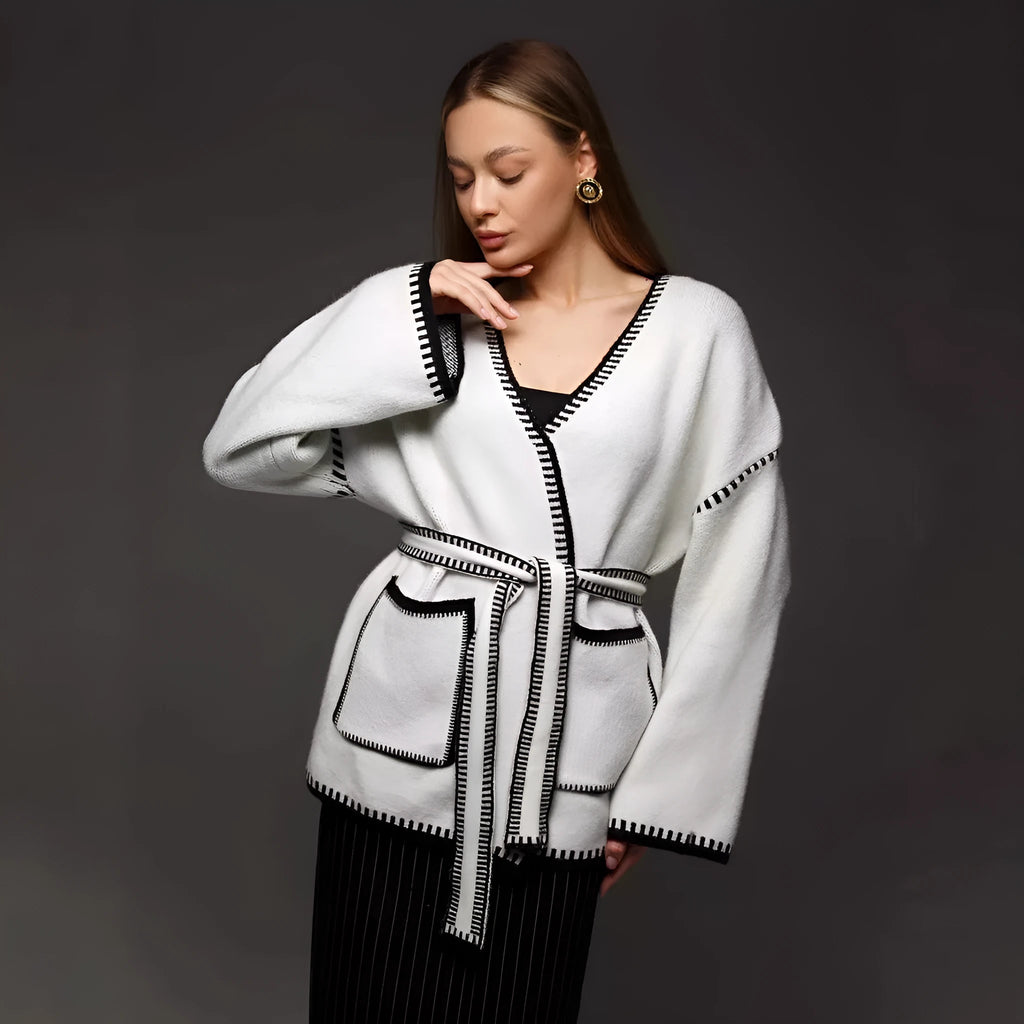 A loose, mid-length knitted cardigan with a front lace-up detail, shown in a camel colour.