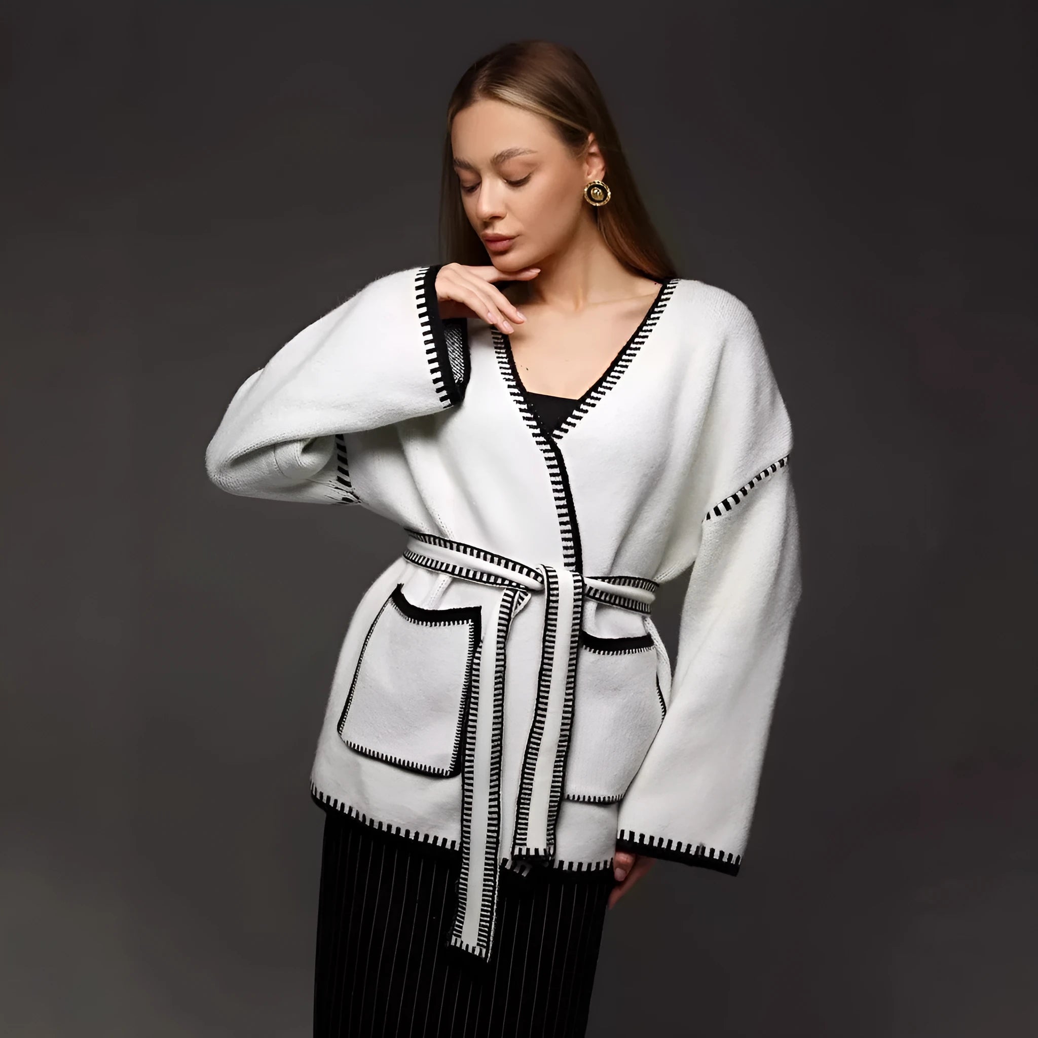 A loose, mid-length knitted cardigan with a front lace-up detail, shown in a camel colour.