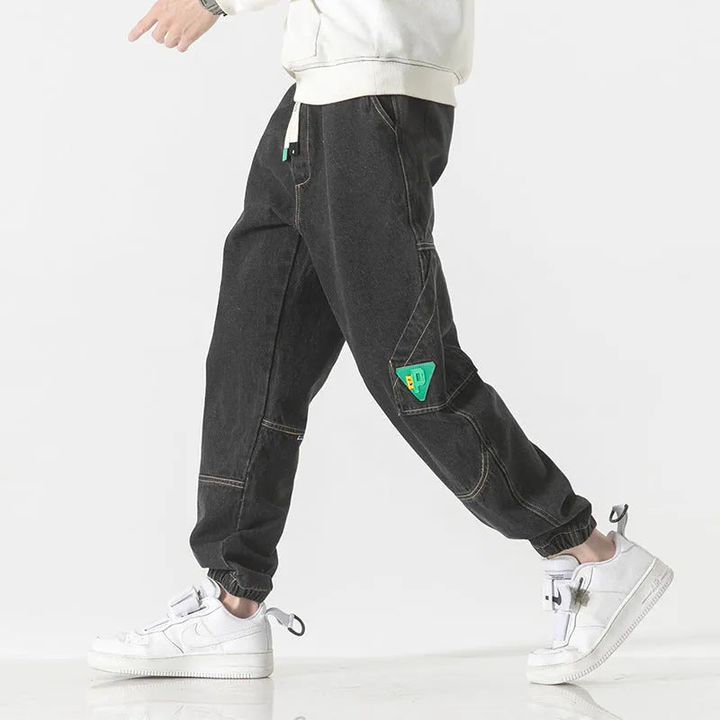 Men's loose-fit tapered cotton trousers in grey on a hanger.