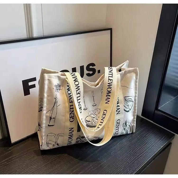 Large canvas tote bag with printed design, featuring two fabric handles, shown in available colour style options.