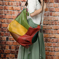 Brown cowhide leather travel shoulder bag with stitching detail, shown with a laptop and tablet inside.