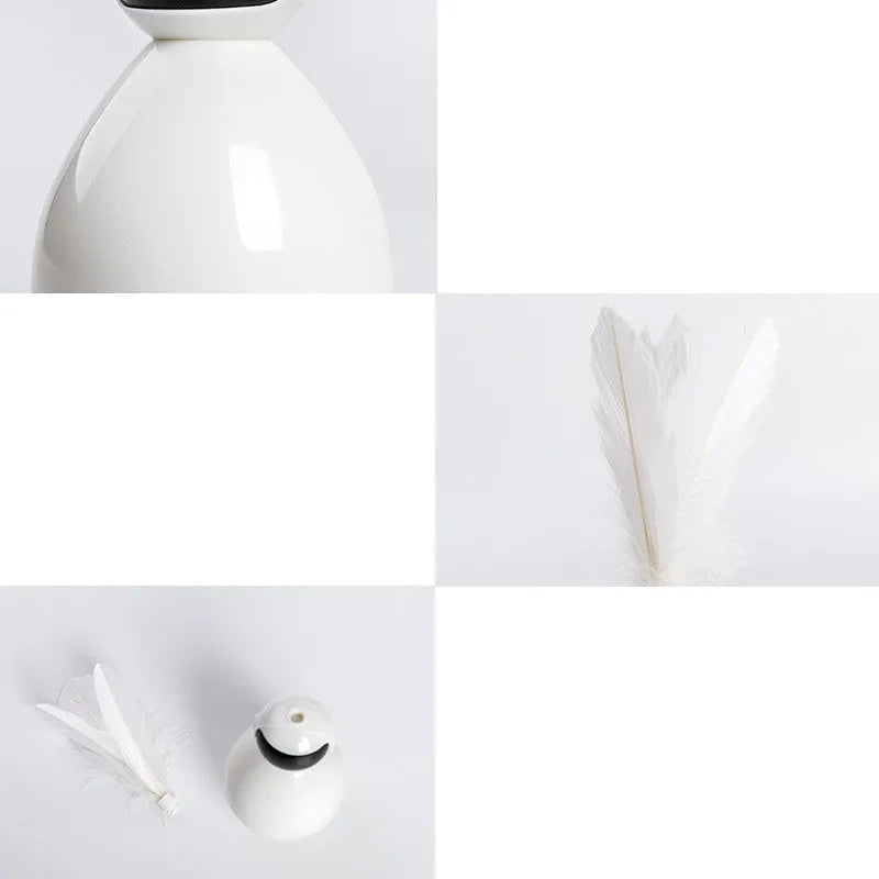 Tumbler cat toy in white with three replacement feathers on a light background