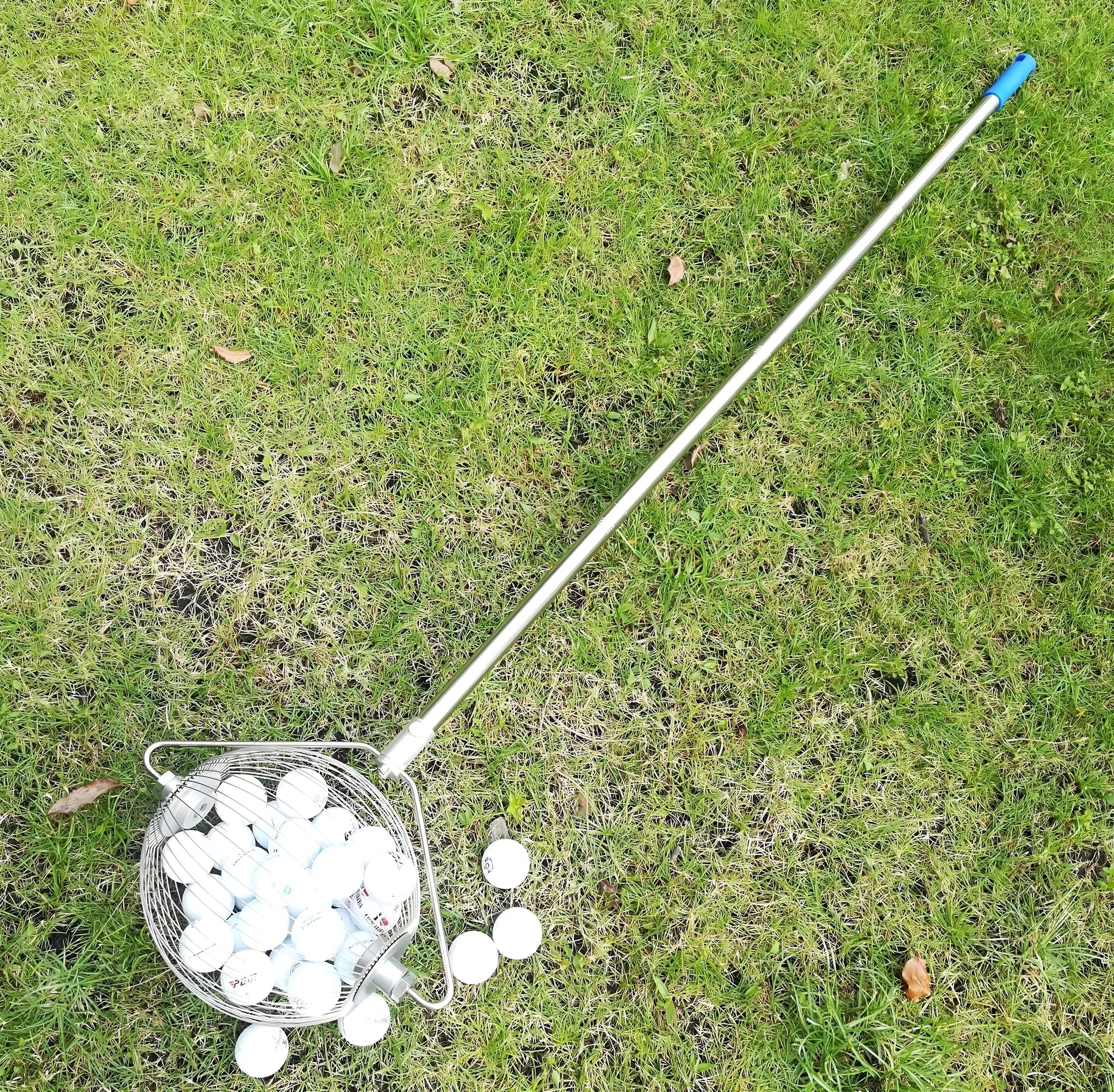 Metallic coloured stainless steel golf ball picker tool on a driving range turf.